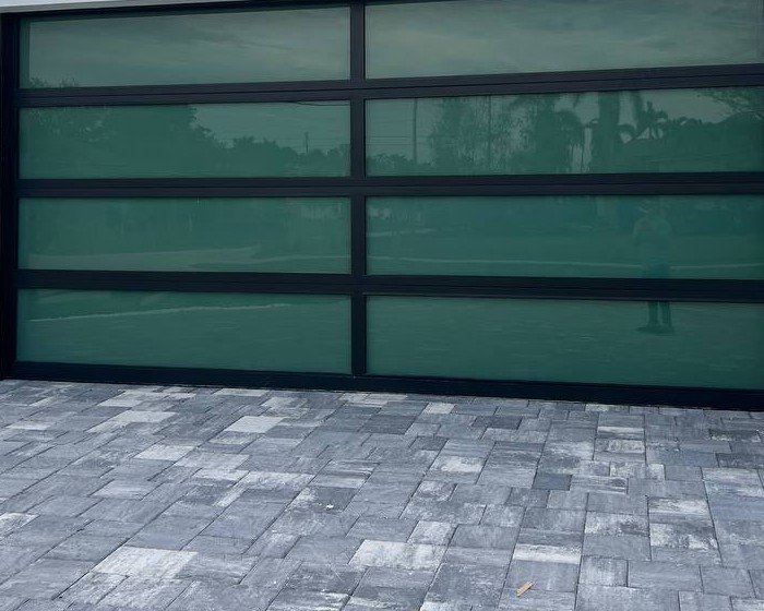 Close detail of laminated full-view impact glass panels and slim black aluminum rails on an AA Impact door