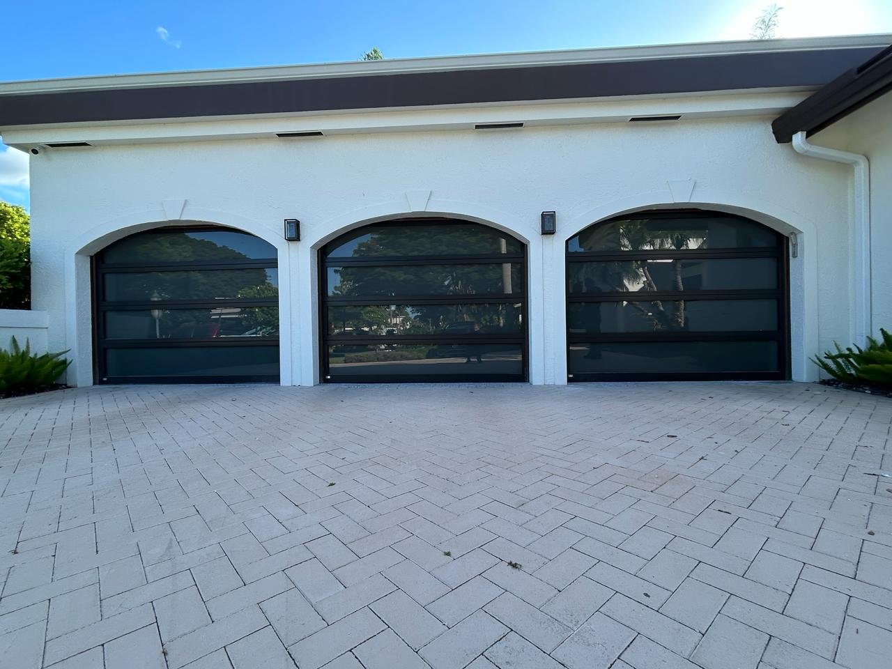 AA Impact Series 1600 impact doors — three arched full-view impact glass garage doors on a luxury South Florida residence