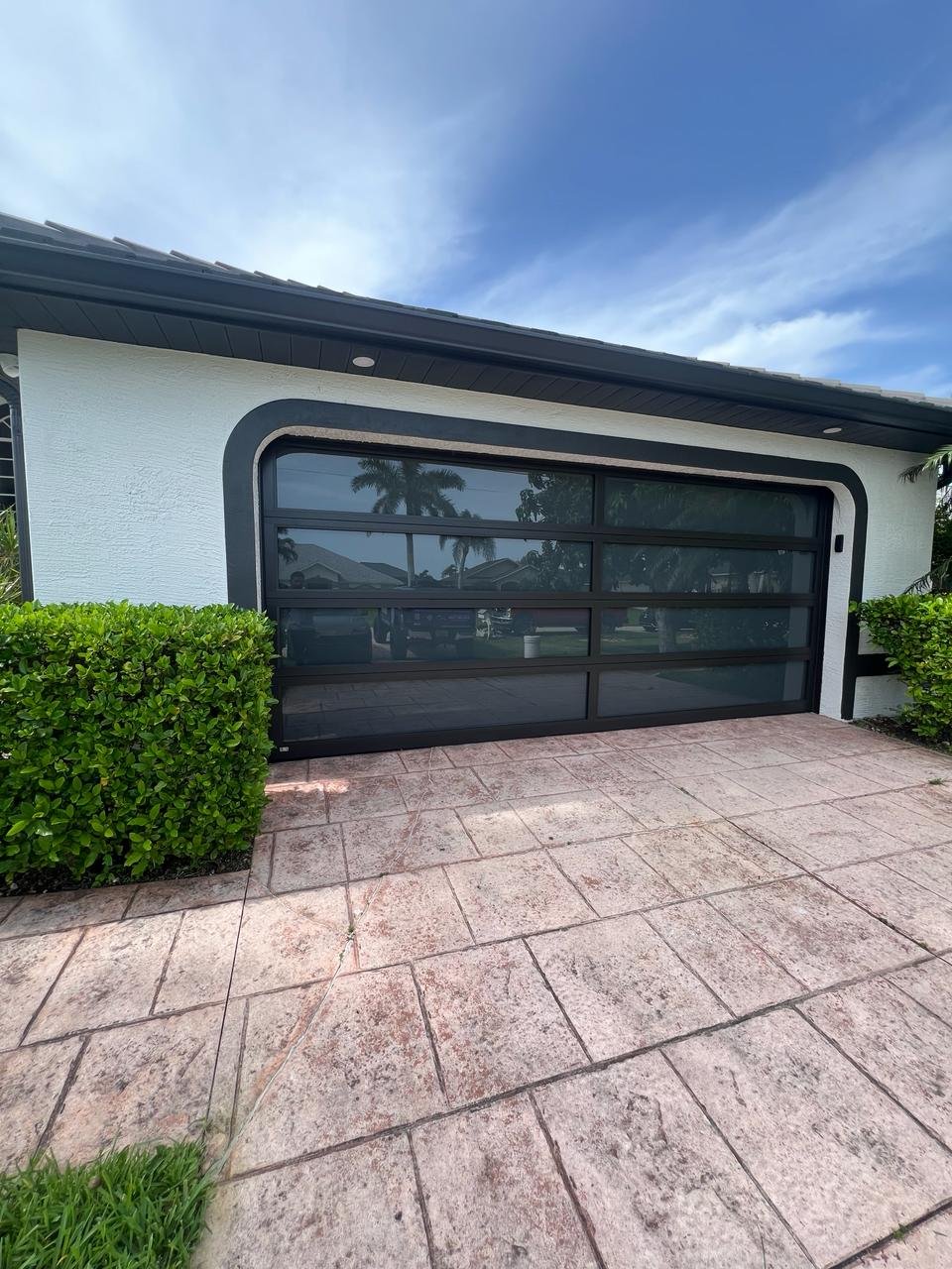 AA Impact Series 1200 full-view impact door — a single clean full-view impact glass door with a curved black surround on a South Florida home